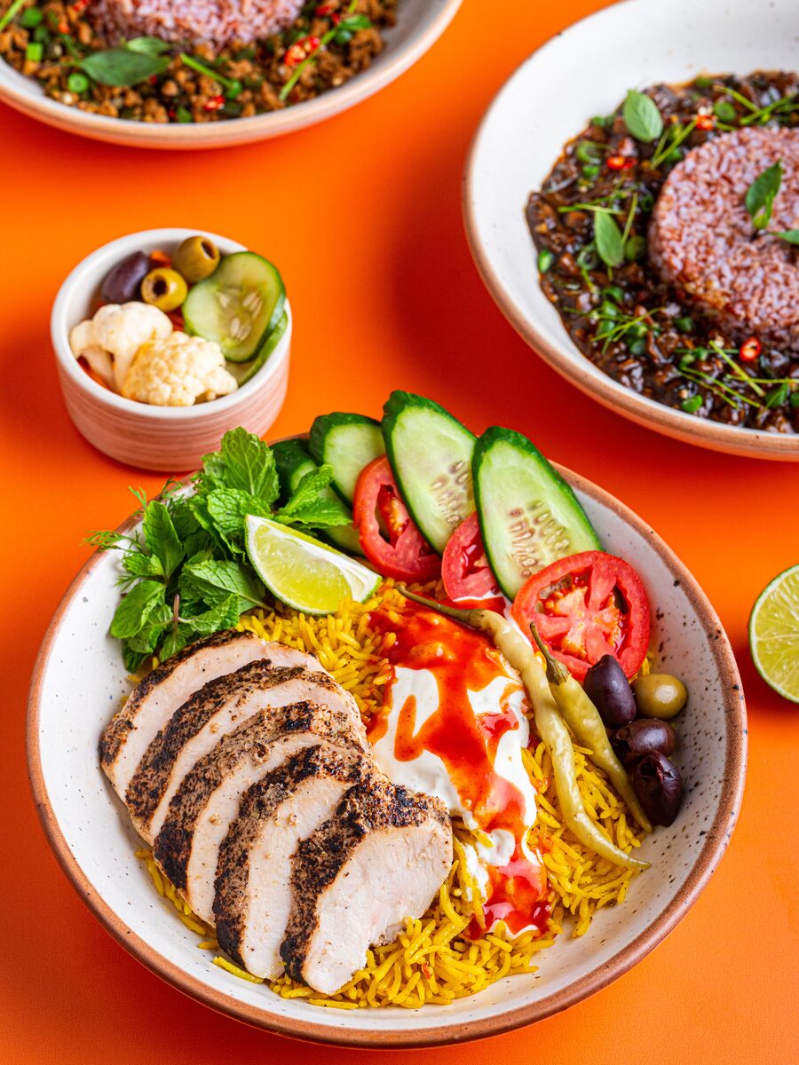 Shawarma chicken rice bowl with yoghurt, chilli oil, olives, and fresh vegetables
